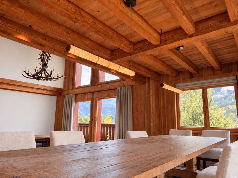 Suspensions linéaires au-dessus de la table d’un chalet ouvert sur les montagnes.