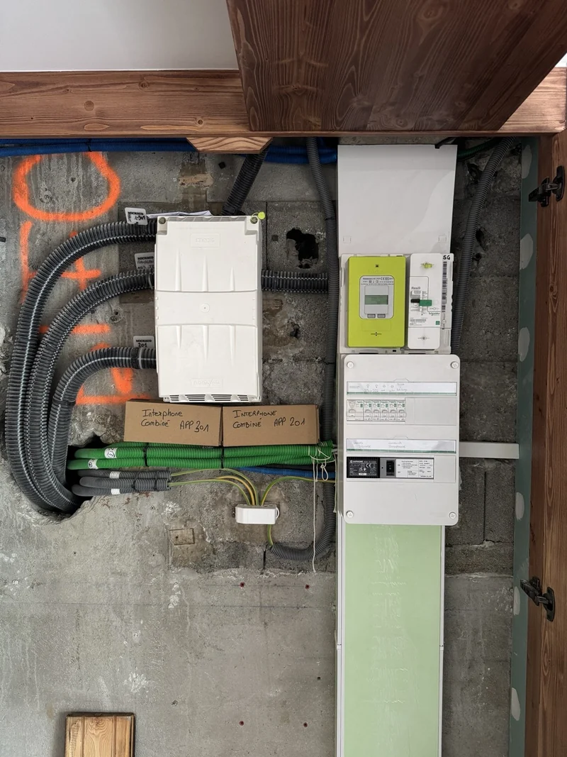 Tableau électrique et compteur dans un espace technique en bois.